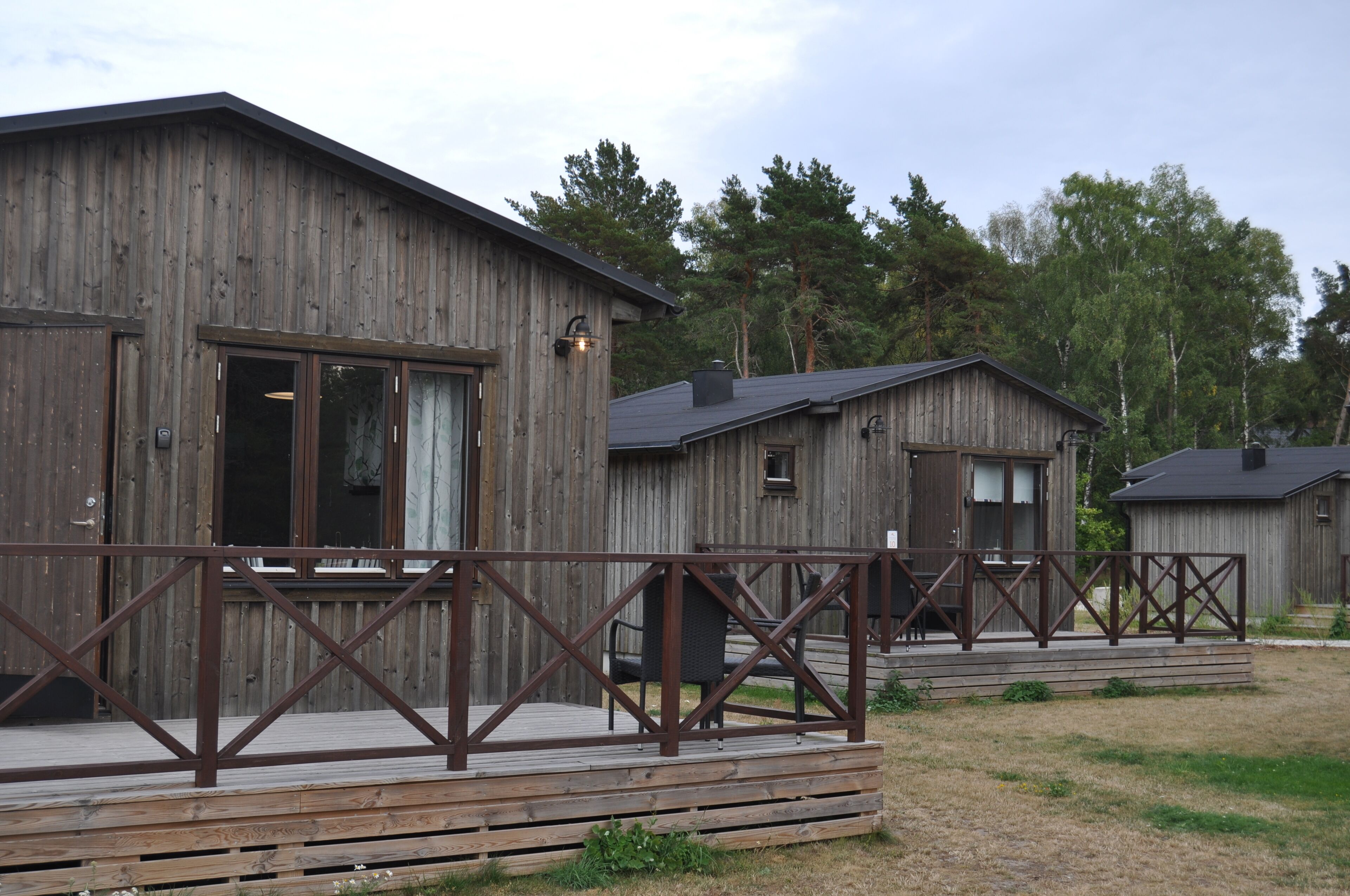 A wooden cabin with a deck and a metal railing.