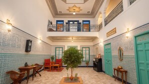 Un vestíbulo amplio con un área de estar central, una planta de interior peque ña y una escalera que sube a un nivel superior.