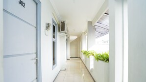 A hallway with a door labeled "302", air conditioning units, and a plant on the wall. - Hotel O Graha Marina (Surabaya)