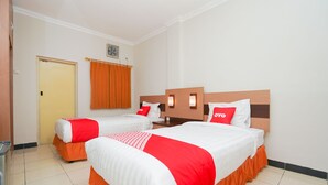 A hotel room with two beds, each with a red and white bedspread, a wooden headboard, and a red pillow with "OYO" branding. - Hotel O Graha Marina (Surabaya)