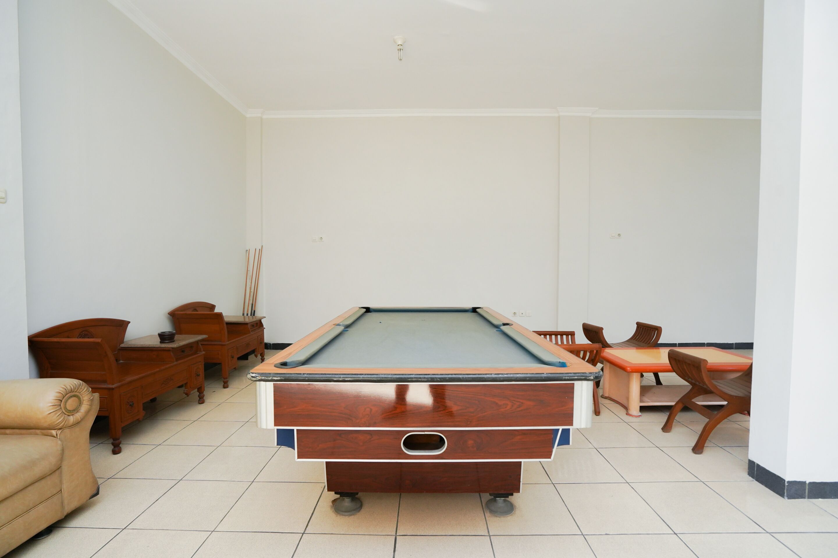 A room with a pool table, wooden furniture, and a tiled floor.