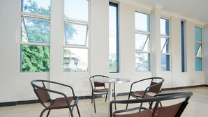 A room with a round table and four chairs, large windows with blinds, and a tiled floor. - Hotel O Graha Marina (Surabaya)