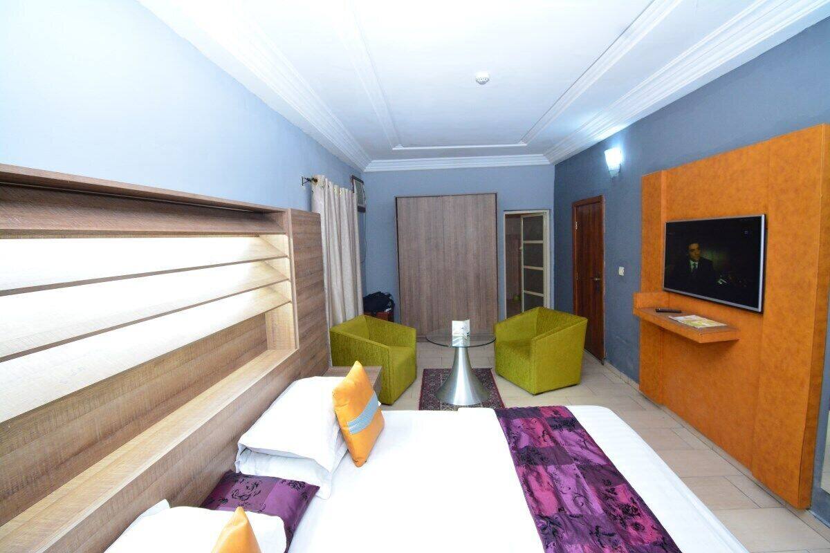 A hotel room with a bed, a TV, a desk, and a seating area with chairs.