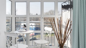 Una habitación luminosa con ventanas amplias, una mesa blanca y sillas.