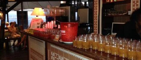 Un espace bar avec un comptoir, des verres et un seau rouge.