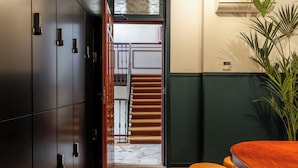 A hallway with a wooden staircase, a potted plant, and a bar area. - Colectia Stays Atocha (Madrid)