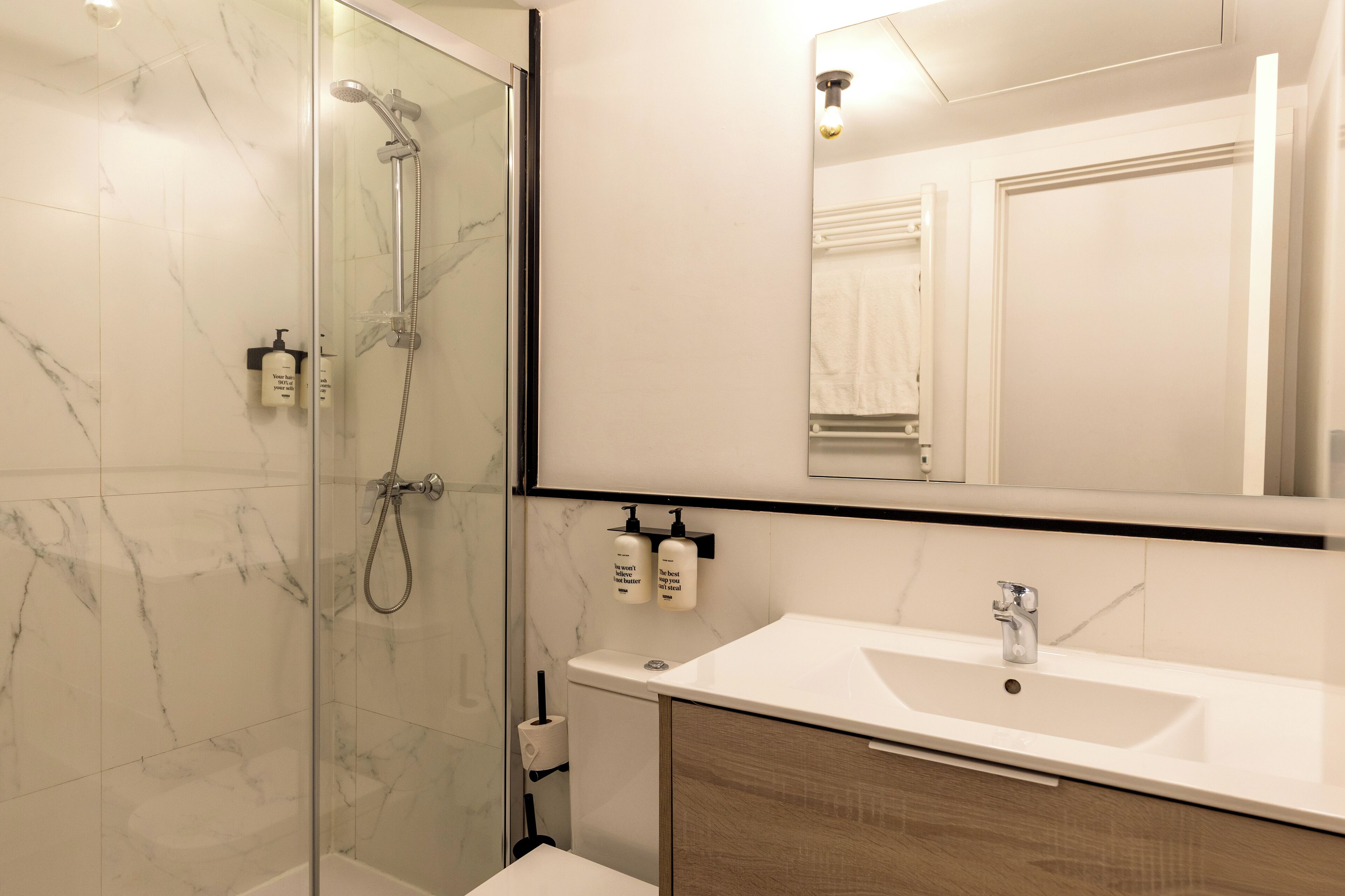 A modern bathroom with a glass-enclosed shower, a white sink, and a mirror above the vanity.