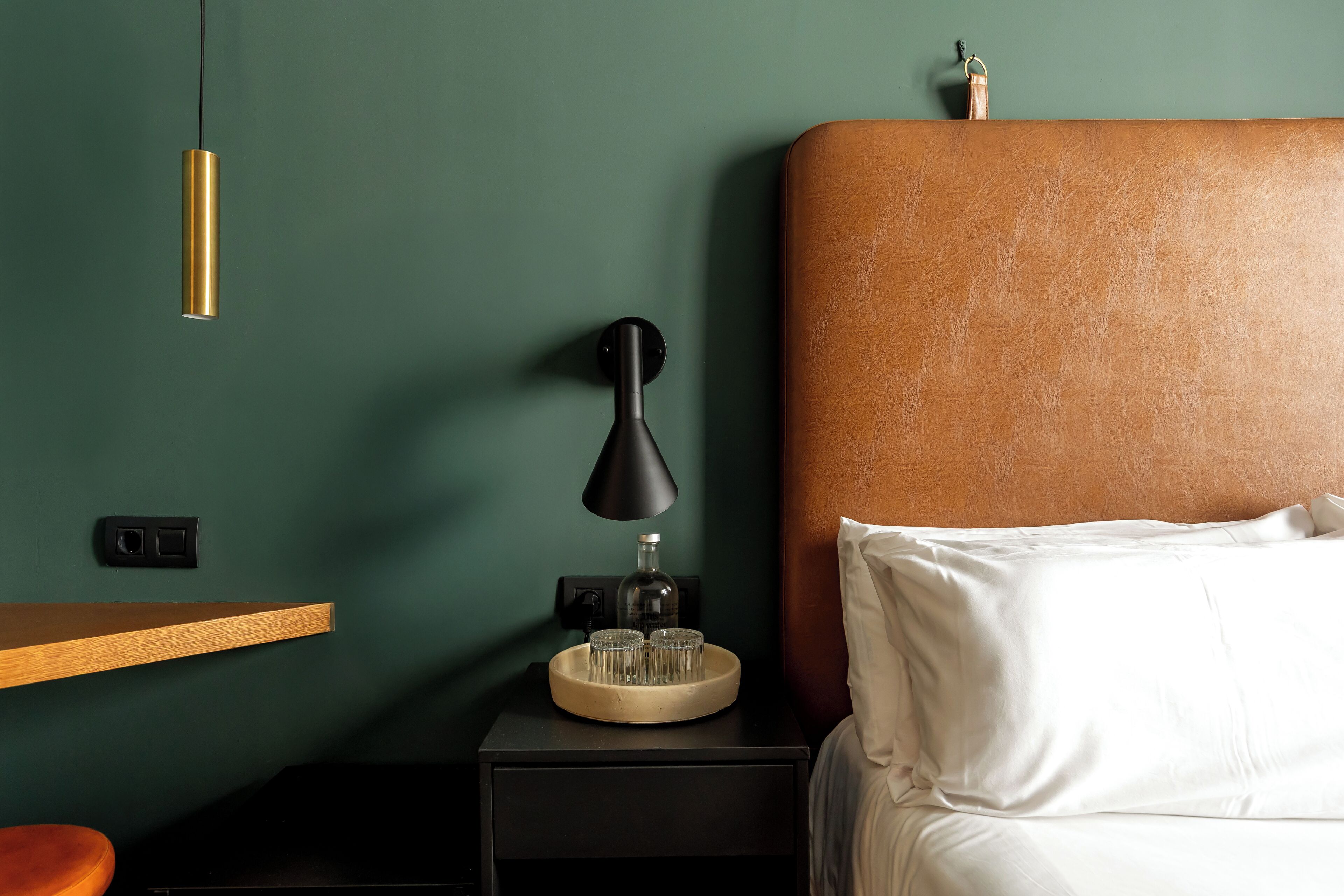 A neatly arranged bedroom with a bed, bedside table, lamp, and a wall-mounted light fixture.