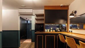 A modern kitchen with a bar area, wooden cabinets, and bar stools. - Colectia Stays Atocha (Madrid)
