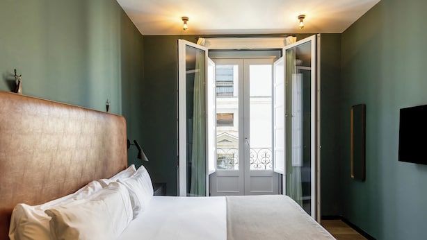 A hotel room with a bed, a wardrobe, a television, and a balcony with a view. - Colectia Stays Atocha (Madrid)