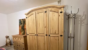 A bedroom with a wooden wardrobe, a bedside table, a chair, and a coat rack. - Ferienwohnung Romance (Ebersbach)