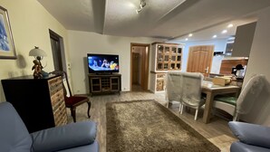 A living room with a television, a coffee table, and two armchairs. - Ferienwohnung Romance (Ebersbach)