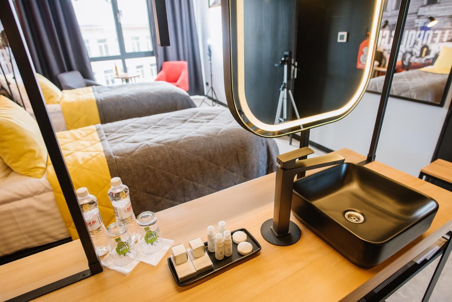 Ein Hotelzimmer mit einem Bett, einem Schminktisch mit Spiegel, einem Waschbecken und Pflegeprodukten auf der Ablagefläche.