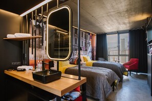 A modern hotel room with two beds, a large mirror, a wooden desk, and a cityscape view. - !FEST Hotel Lemkivska (Lviv)