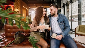 A couple sitting on a leather couch in a modern cafe with large windows and indoor plants. - !FEST Hotel Lemkivska (Lviv)