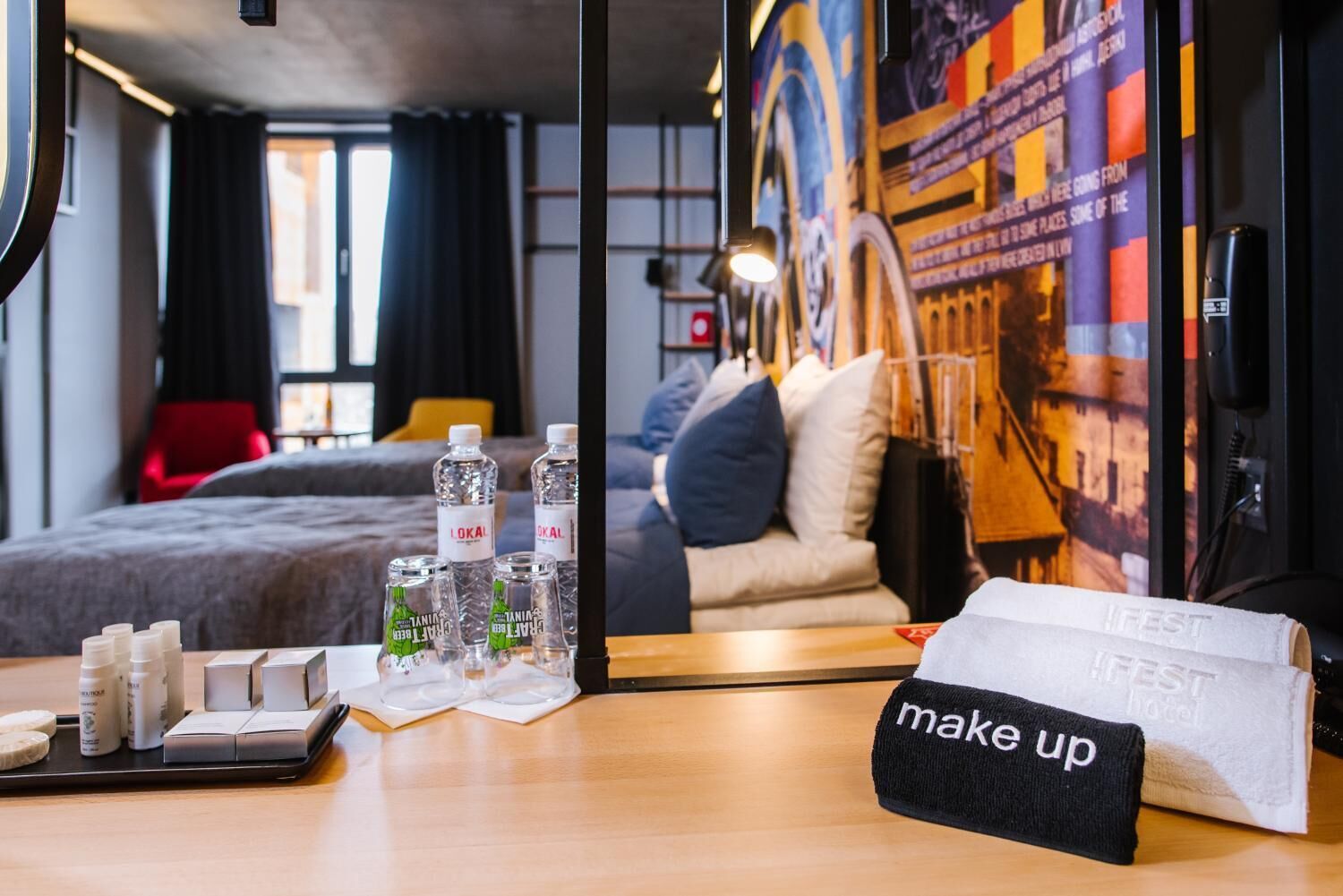Habitación de hotel con cama, espejo, mesa con artículos de aseo e indicación 'maquillaje'.