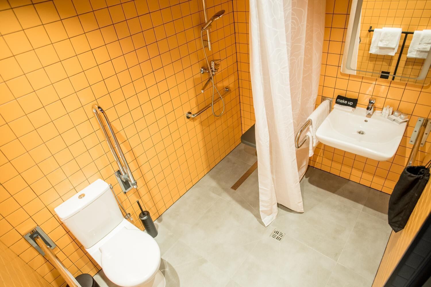 Un baño con inodoro blanco, lavamanos y ducha con puerta de cristal.