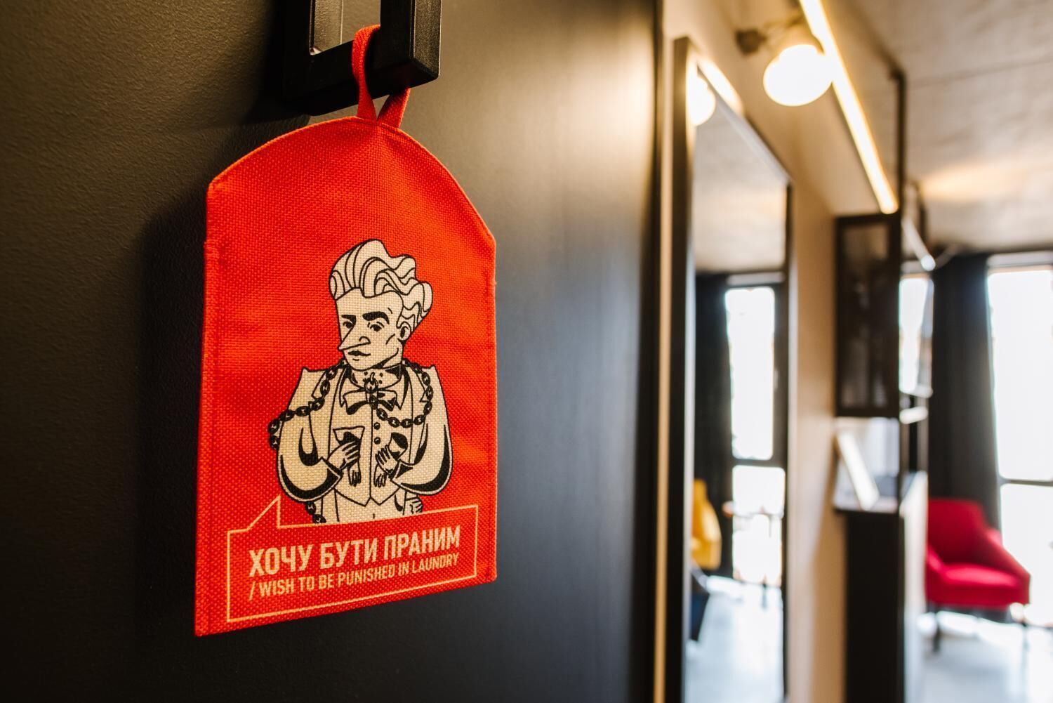 A red sign with a cartoon character and text in a foreign language, mounted on a wall in a hallway.