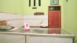 A restroom with a wooden door, a sink, and a glass partition. - OYO 1639 Penginapan Anggrek Syariah 1 (Probolinggo)