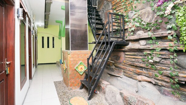 A staircase with a metal railing leading to a stone wall with greenery. - OYO 1639 Penginapan Anggrek Syariah 1 (Probolinggo)
