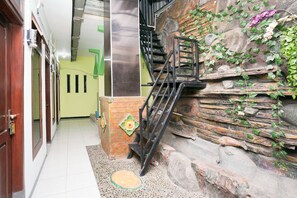 A staircase with a metal railing leading to a stone wall with greenery. - OYO 1639 Penginapan Anggrek Syariah 1 (Probolinggo)
