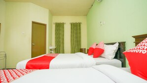 A hotel room with two beds, a sink, and green curtains. - OYO 1639 Penginapan Anggrek Syariah 1 (Probolinggo)