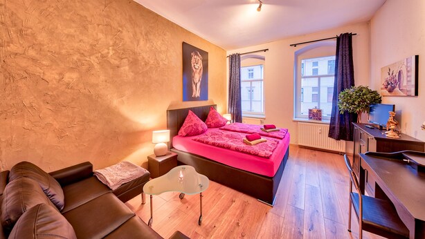A bedroom with a bed, bedside table, lamp, and a desk with a chair. - Ferienwohnung Dresden (Dresden)