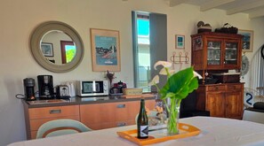 A kitchen with a coffee maker, toaster, microwave, and cabinets. There is a framed picture on the wall and a window with a view.
