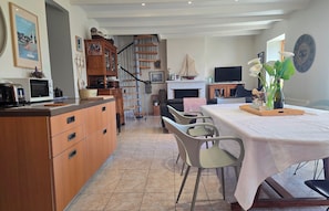A spacious kitchen with wooden cabinets, a dining area with a table and chairs, a staircase, and a fireplace.