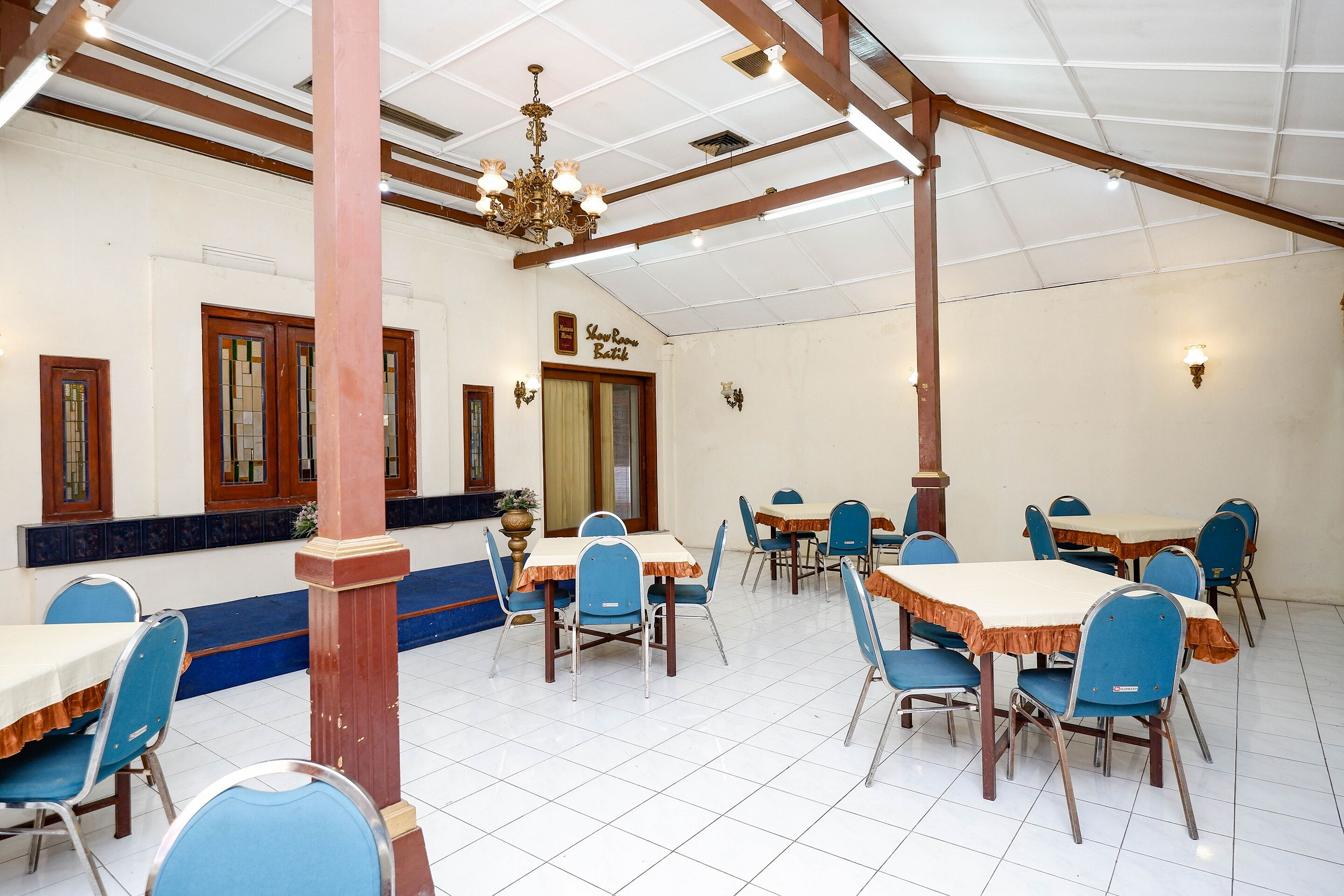 A dining area with multiple tables and chairs, wooden beams, and a chandelier.