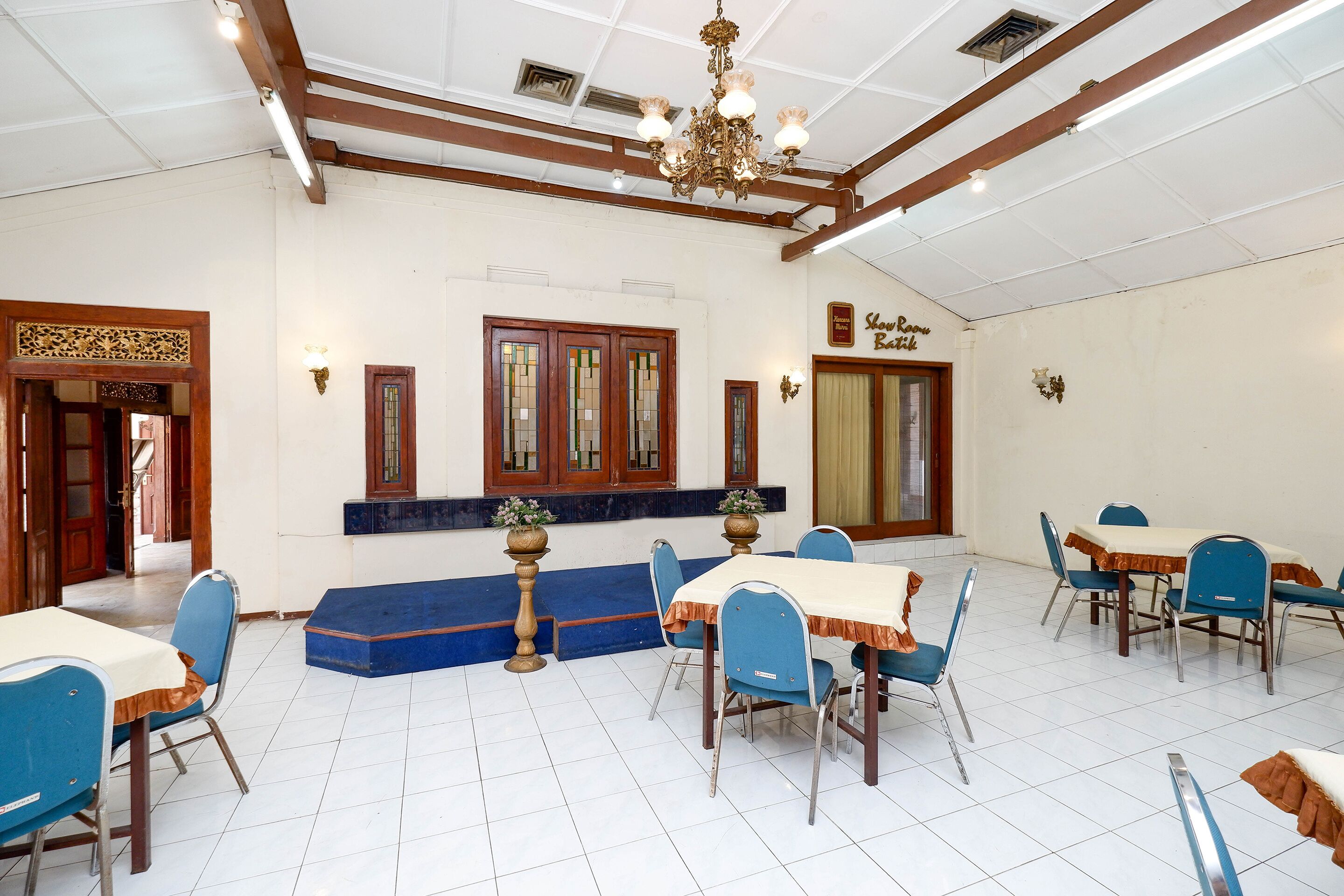A dining area with tables and chairs, a chandelier, and a sign indicating a show room.