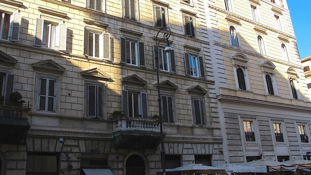 A multi-story building with classical architecture, featuring symmetrical windows and a balcony.