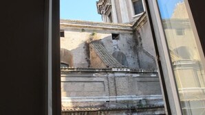 A view through a window of an old building with classical architecture, including columns and a detailed facade.