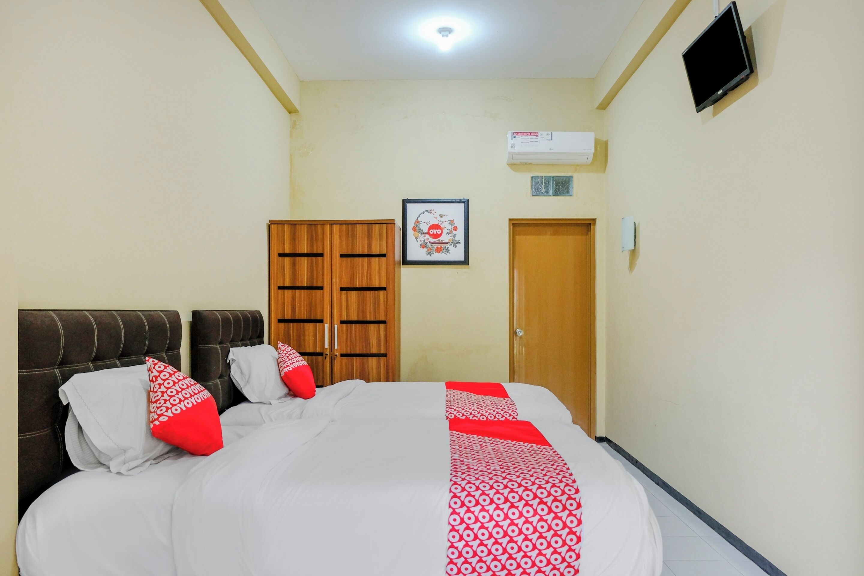 A hotel room with a bed, a wardrobe, a television, and an air conditioning unit.