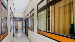 A corridor with multiple windows and doors, leading to rooms. - OYO 1342 Uniga Malang Family Residence (Malang)