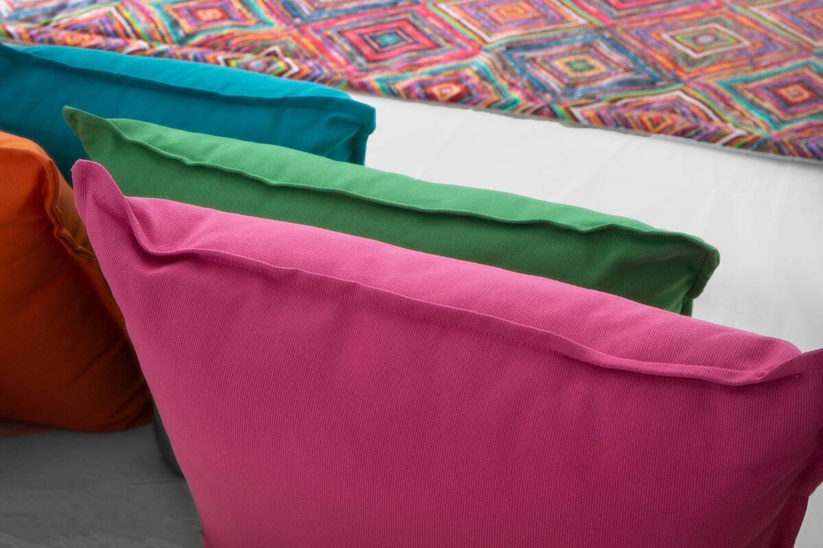 A white sofa with colorful cushions and a patterned rug.