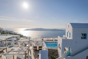 Ein Hotel an der Küste mit Pool, Sitzgelegenheiten im Freien und Meerblick.