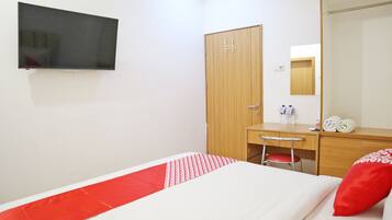 A hotel room with a bed, a desk, a chair, a television, a wardrobe, and a mirror.