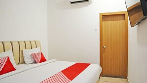Una habitación de hotel con una cama, una puerta de madera y un televisor montado.