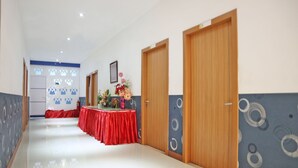 Un pasillo con una mesa roja, puertas de madera y paredes con diseños.