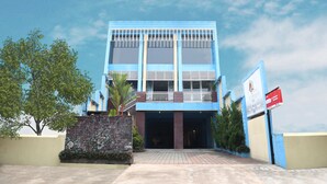 Un edificio de dos pisos con fachada azul, un balcón y un muro de piedra con vegetación.