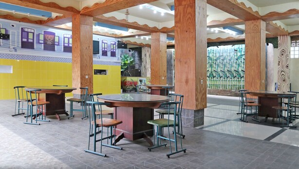 Un restaurante con vigas de madera, paredes de azulejos y varias mesas y sillas.