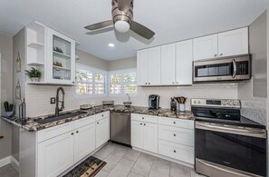 A modern kitchen with white cabinets, a stainless steel microwave, and a built-in oven.