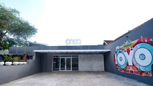 Un edificio con un gran letrero de 'OYO', una entrada de vidrio y un mural en la pared derecha.