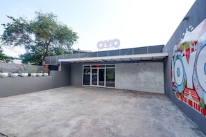 A modern building with a large 'OYO' sign, a concrete courtyard, and a mural on the right wall. - OYO 2055 Perdana Kasih (Klaten)