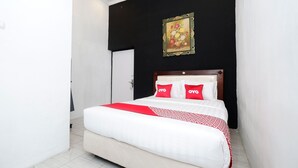 Una habitación de hotel con cama, un cuadro en la pared y una puerta.