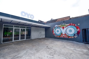 A building with a large 'OYO' sign, a glass entrance, and a mural with travel-related imagery. - OYO 2055 Perdana Kasih (Klaten)