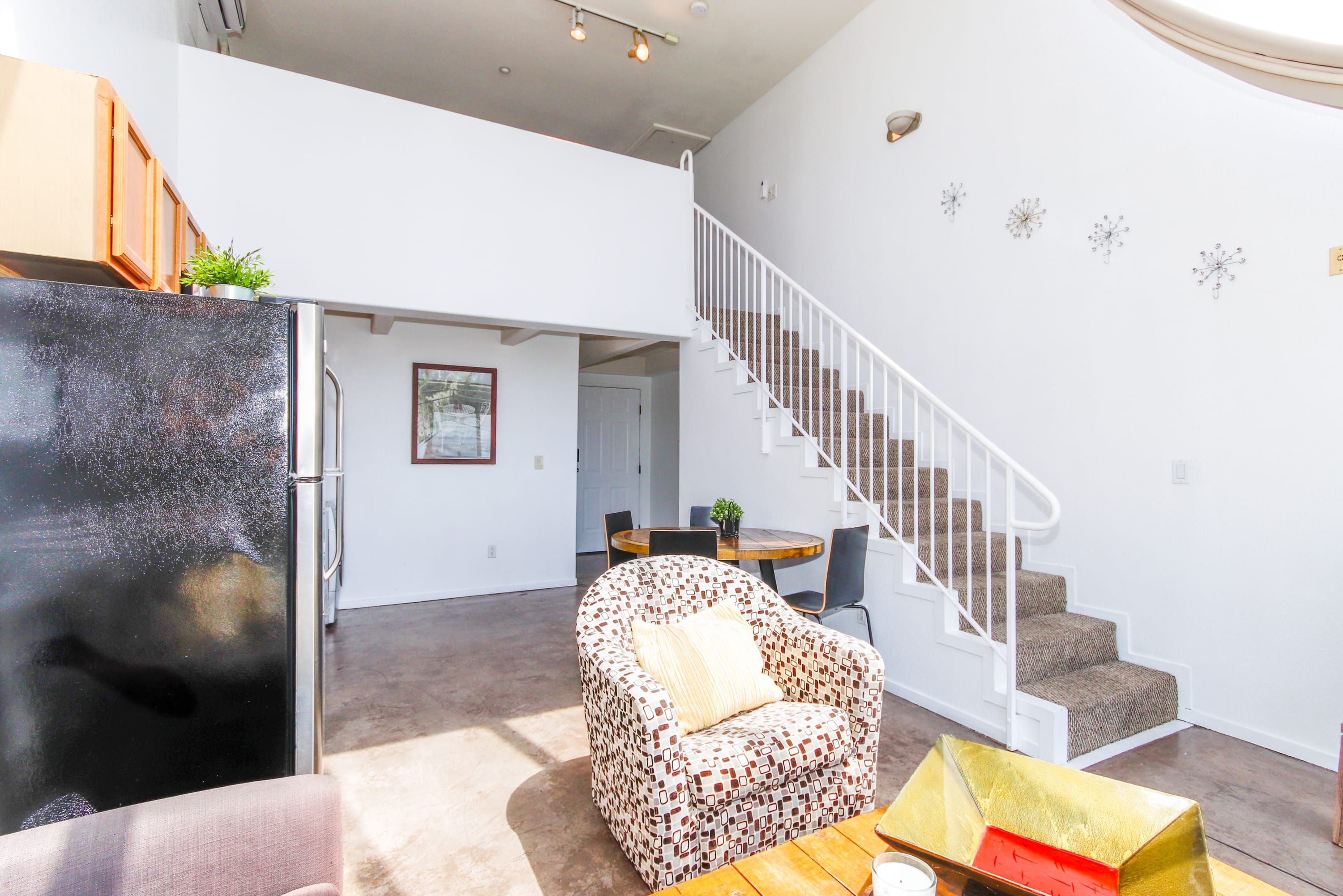 A living room with a sofa, a coffee table, a staircase, and a dining area.