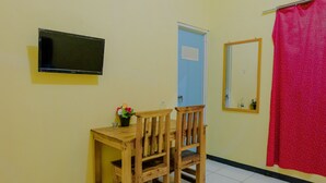 A room with a wooden desk, two chairs, a television mounted on the wall, a door, a mirror, and a red curtain. - SPOT ON 1976 Hamana Beach Inn (Pacitan)