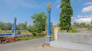 A paved pathway with blue and gold pillars, a concrete wall, and a sign for "Maharashtra Museum". - SPOT ON 1976 Hamana Beach Inn (Pacitan)